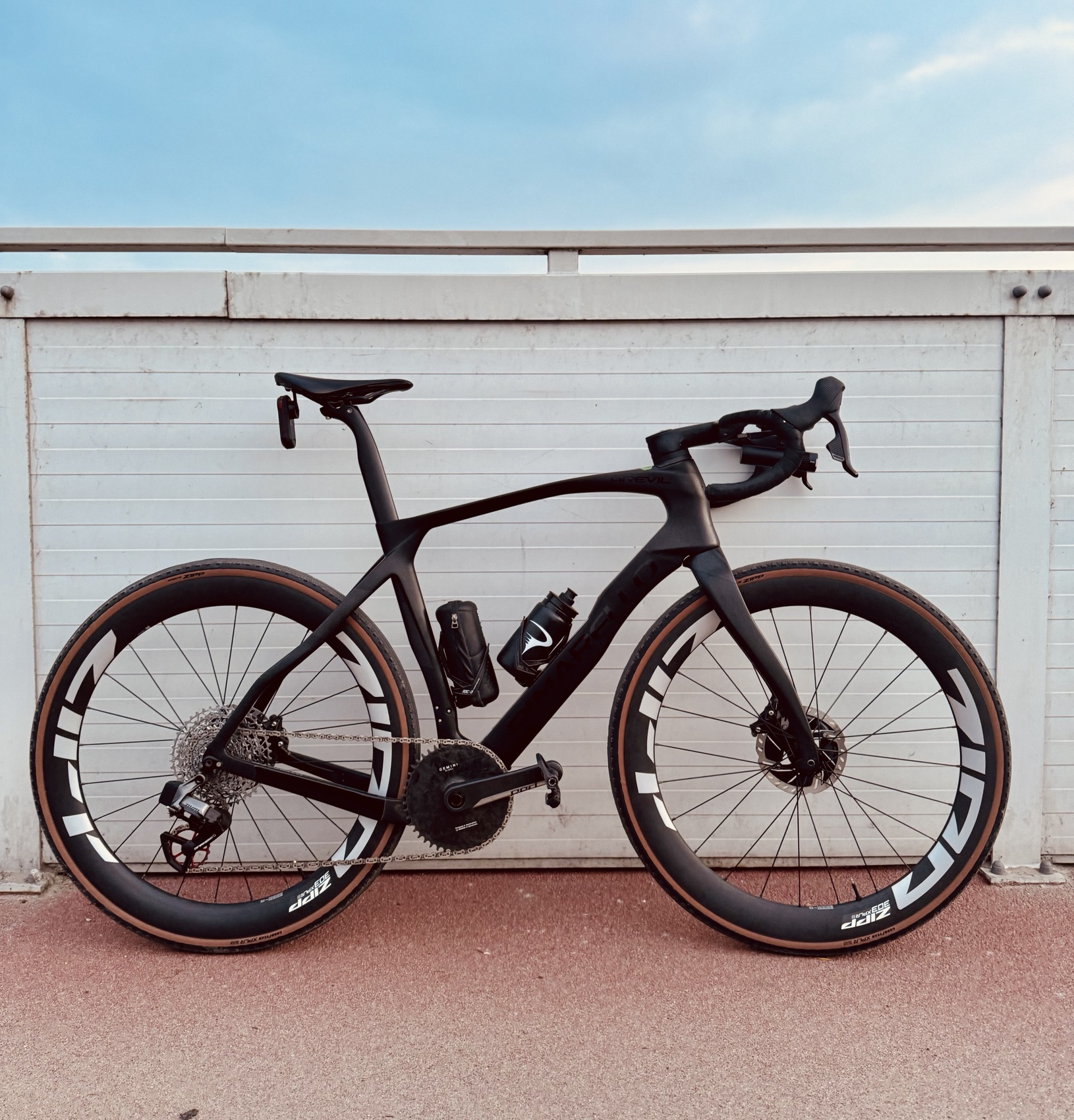 Black gravel bike photographed side-on against a clean wall